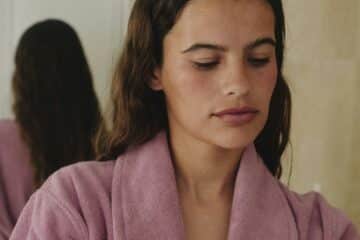 an attractive lady in a pink dressing gown prepearing to put a face mask on.