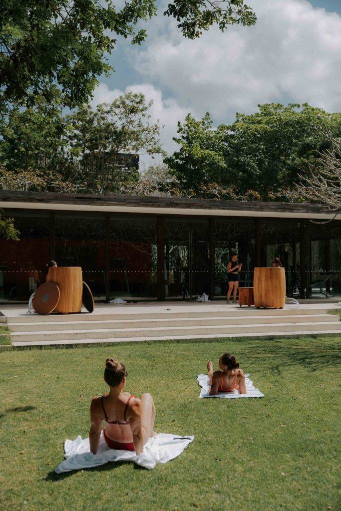 2 girls sunbathing, while watching their friends take a cold plunge