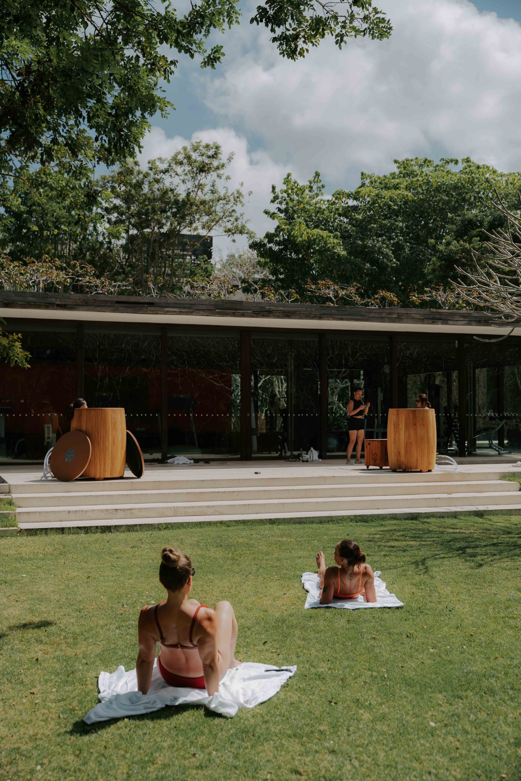 2 girls sunbathing, while watching their friends take a cold plunge