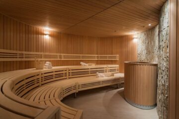 Traditional dry sauna room with timber walls, bench seating, and soft steam in amber light