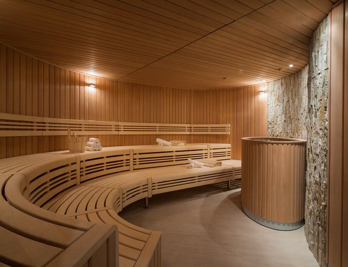 Traditional dry sauna room with timber walls, bench seating, and soft steam in amber light