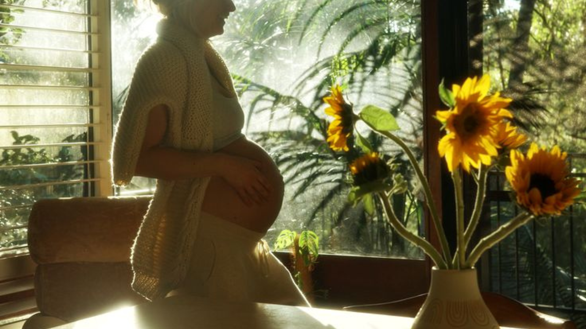 Quiet, intimate pregnancy-adjacent silhouette in warm morning light, reflecting cautious decision-making about cold water immersion