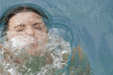 Close-up of hands resting on the edge of a cold plunge with a small timer nearby, illustrating that seconds—not suffering—drive the benefits