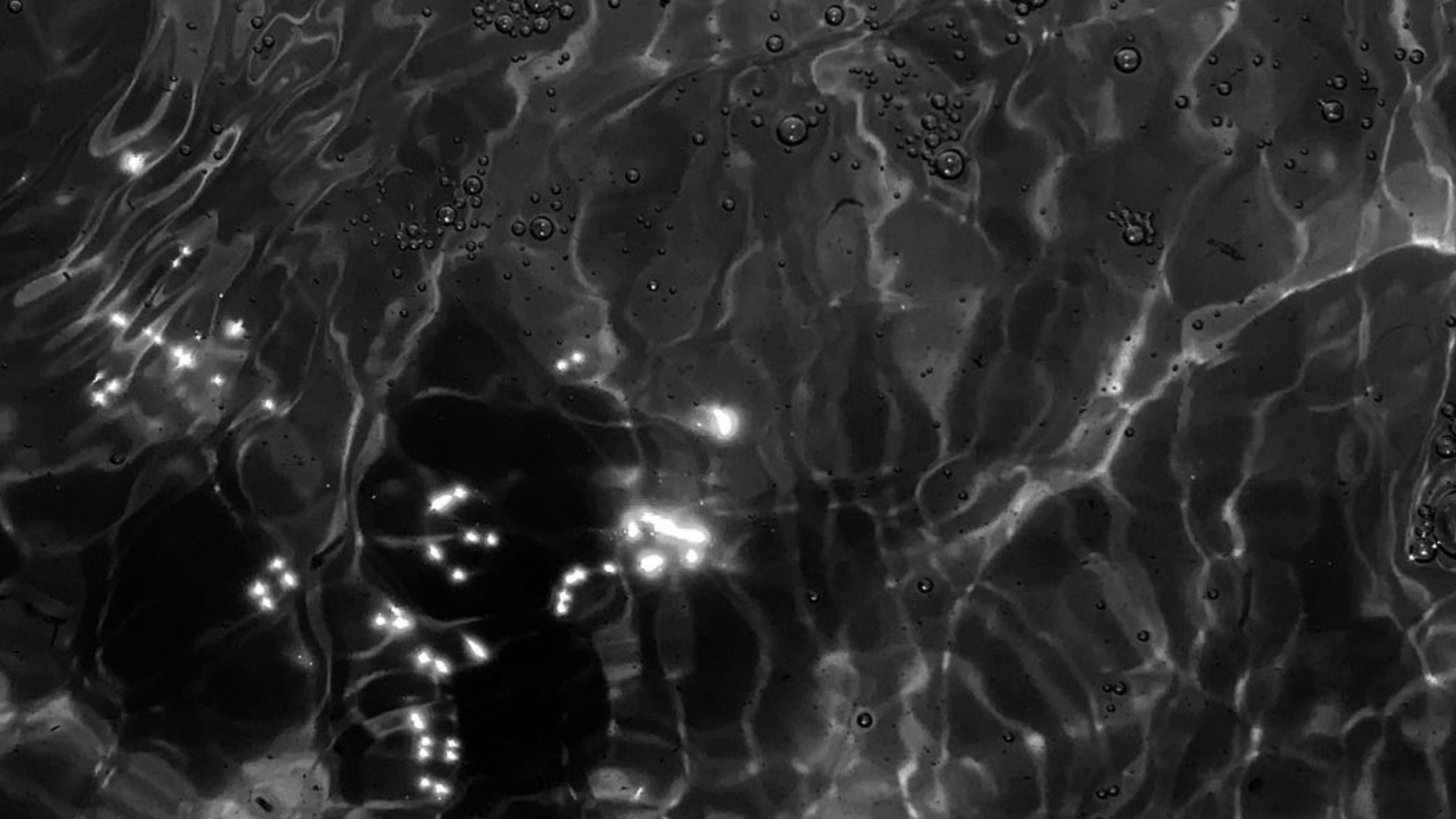 Abstract cold-water surface in low light with subtle steam/condensation and soft ripples, suggesting caution and controlled exposure