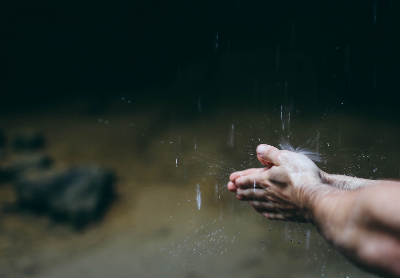 a man with his hands under a waterfall