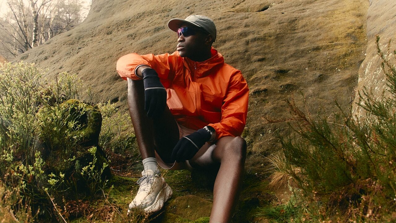 a runner, resting on the side of a hill in an orange jacket. Picture by Joey Bania