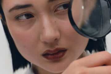 a oriental female scientist looking through a large magnifying glass