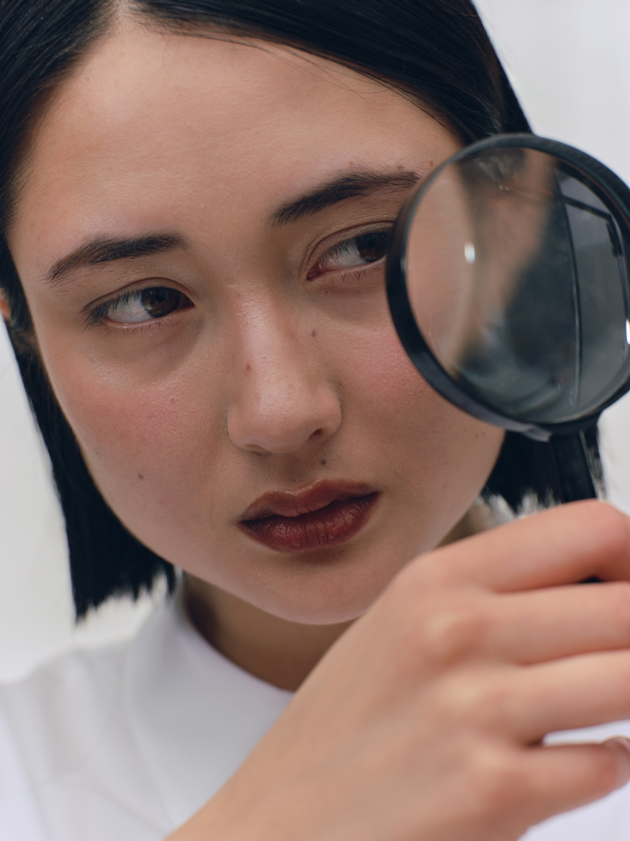 a oriental female scientist looking through a large magnifying glass