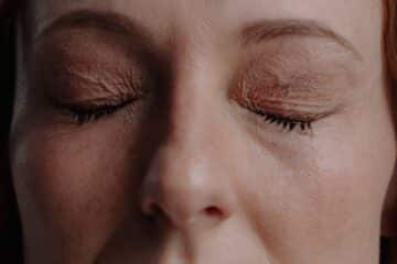 Close up shot of a white woman with her eyes closed in the middle of a meditation.