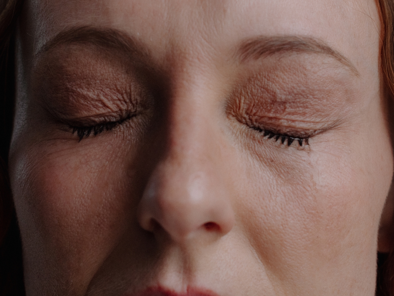 Close up shot of a white woman with her eyes closed in the middle of a meditation.