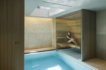 Contrast therapy scene with soft steam near a sauna doorway and a still cold plunge surface in the foreground, illustrating the choice to end on hot or cold