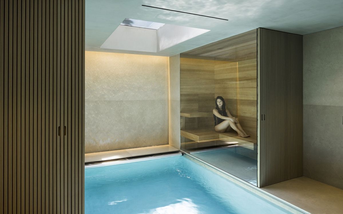 Contrast therapy scene with soft steam near a sauna doorway and a still cold plunge surface in the foreground, illustrating the choice to end on hot or cold